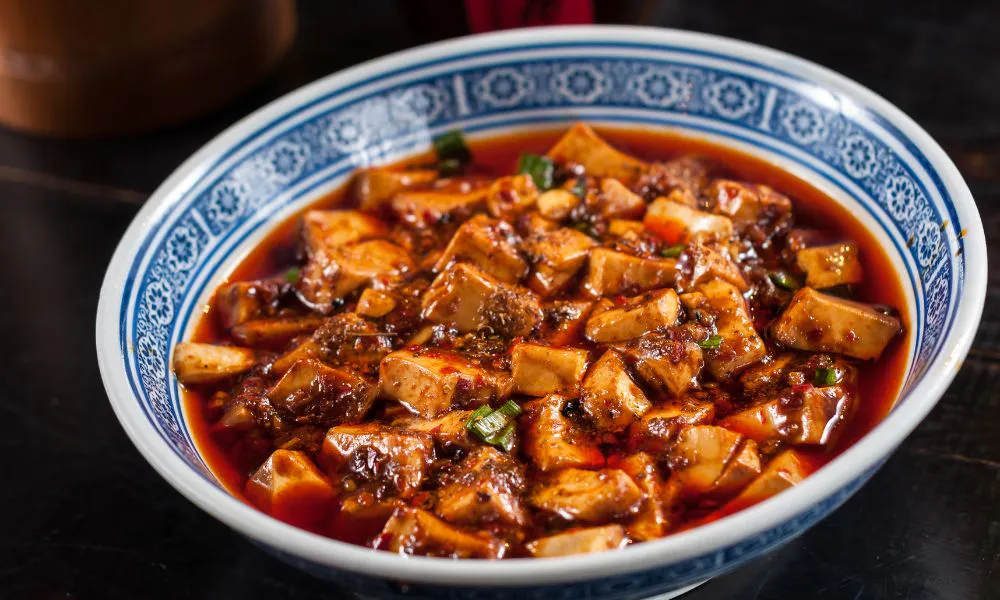 Sichuan mapo tofu, soft tofu cubes in spicy reddish chili sauce garnished with chopped green onions at Eat Time, a Chinese Restaurant in Burien