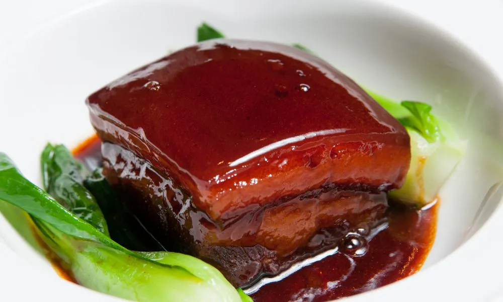 Glazed braised Dongpo pork belly paired with fresh baby bok choy in a simple white ceramic bowl at Eat Time, a Chinese Restaurant in Burien