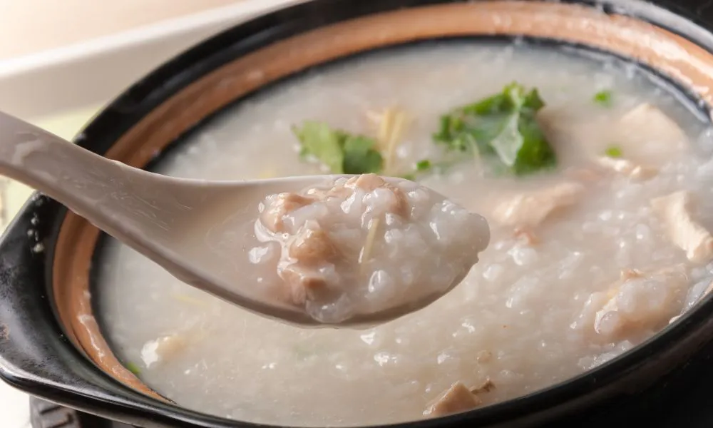 Clay pot chicken congee, creamy rice porridge with tender chicken pieces and fresh cilantro garnish at Eat Time, a Chinese Restaurant in Burien
